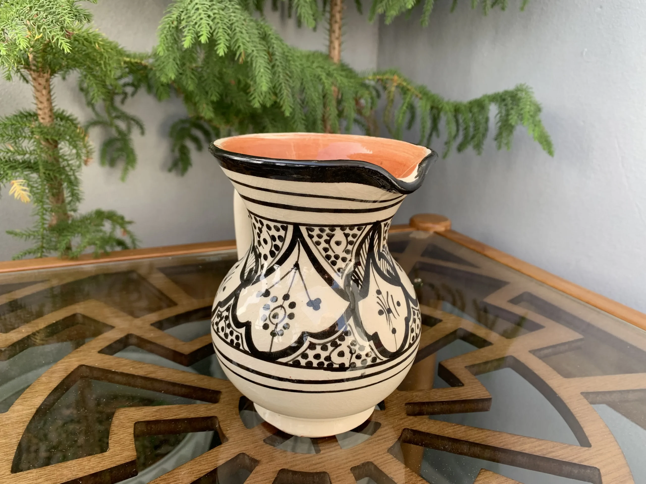 Artisan Moroccan ceramic pitcher and cup on wooden table